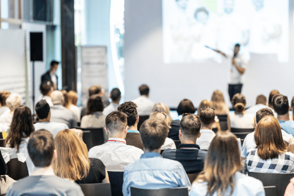 Looking over a crowd to a stage at a conference