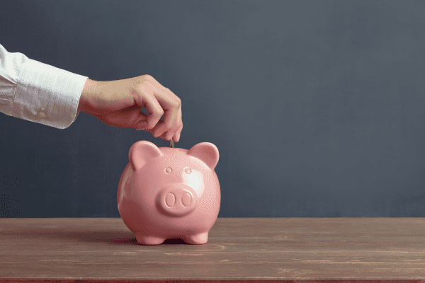 A hand putting a coin into a piggy bank